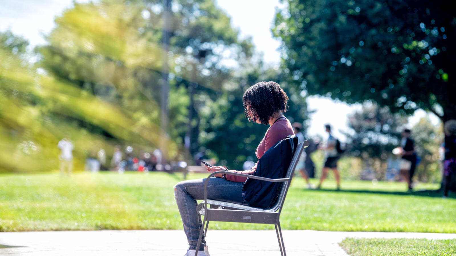 Student sitting on a bench looking at their phone