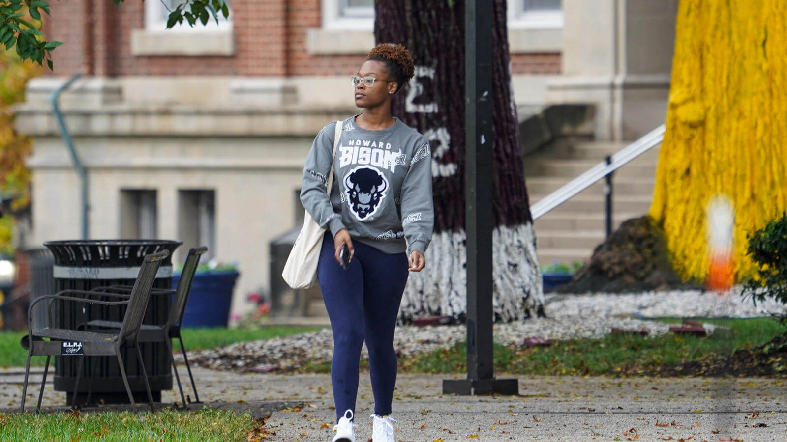 Student walking on campus with a phone